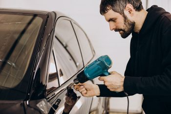 Male worker wrapping car with ptotective foil